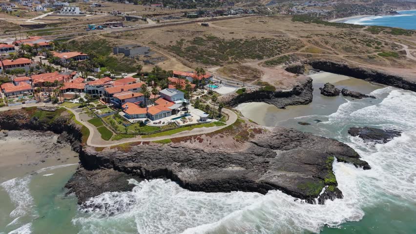 Aerial drone view of a red-roofed resort community on a rocky coastal point in Baja California Mexico.