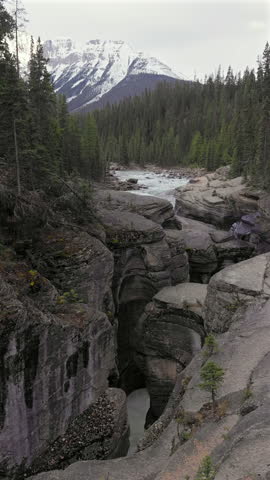 Vertical Video of Mistaya Canyon on a cloudy winter day, showing powerful flowing water carving through narrow rock formations in Banff National Park, Alberta Canada.