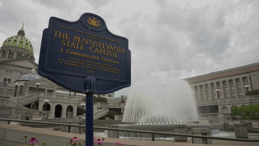 Description:
Tilt and pan establishing shot of the Pennsylvania State Capitol sign and fountain in Harrisburg Pennsylvania on a clear summer day showcasing the historic government complex and surround