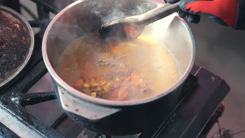 Close-up of Traditional Argentine Beef Stew Simmering and Steaming in Metal Pot with Large Spoon