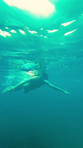 Underwater view of a female snorkeler giving a thumbs up gesture. Woman swimming and snorkeling in the turquoise sea of Puerto Morelos, Mexico.