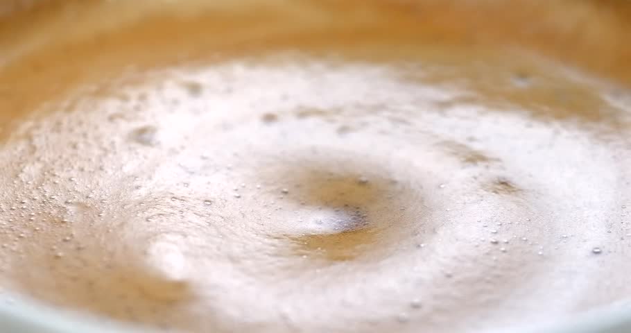 Espresso coffee drop creating a splash and ripple in crema super slow motion