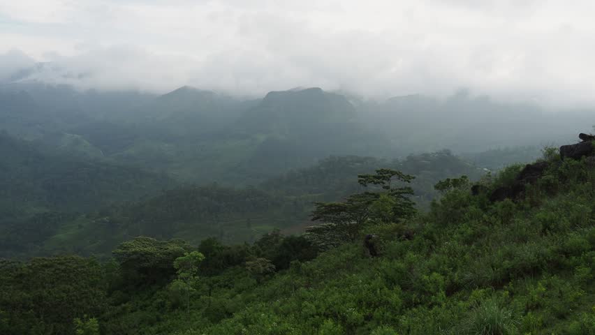 Scenic mountain range landscape emerging from the clouds and mist in a lush green valley