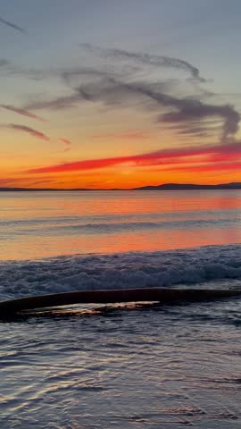 Orange sunset on a PNW beach with driftwood