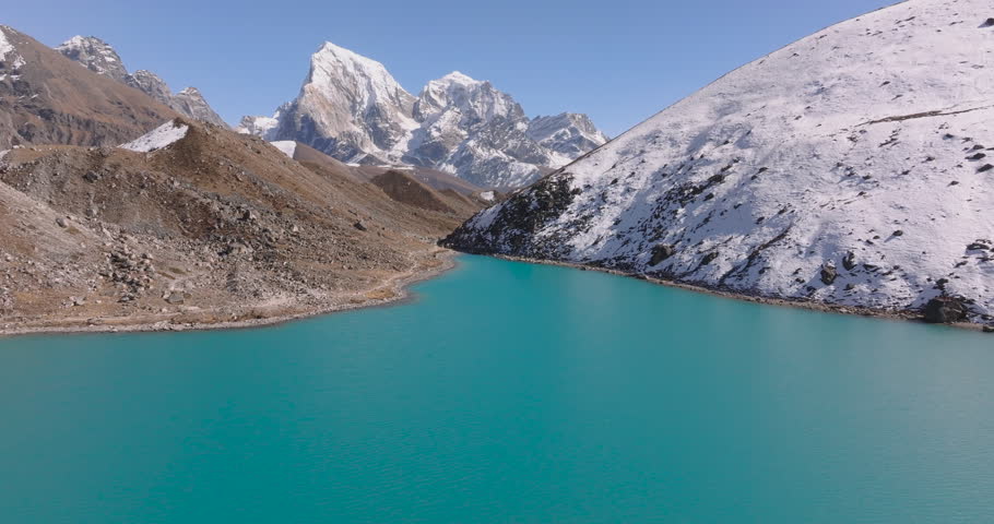 Gokyo Lake, Everest Region, Nepal, drone push-in over the bright turquoise glacial lake toward the snow-covered peak of Cholatse himalayas.