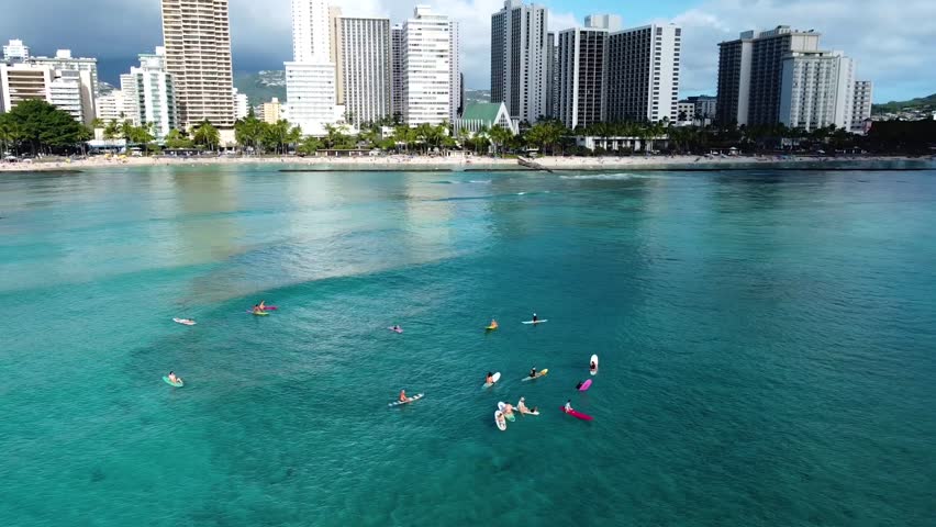 Aerial view of the honolulu skyline with people surfing and paddle boarding in the turquoise waters of the pacific ocean at waikiki beach