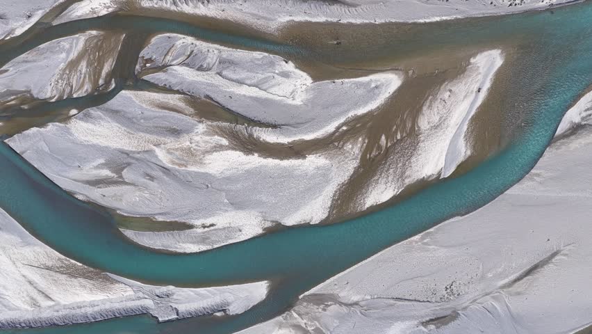 Drone top-down view of turquoise braided river channels cutting through glacial sediment plains in New Zealand
