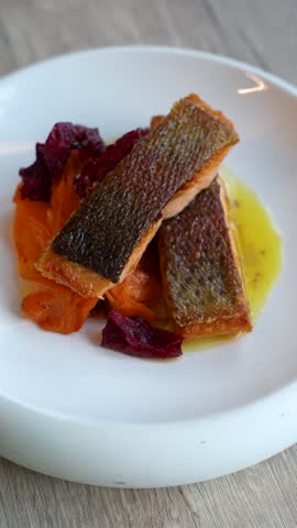 Vertical close up, pan-seared rainbow trout with sweet potato and beurre blanc sauce, filmed in a restaurant in Slovenia