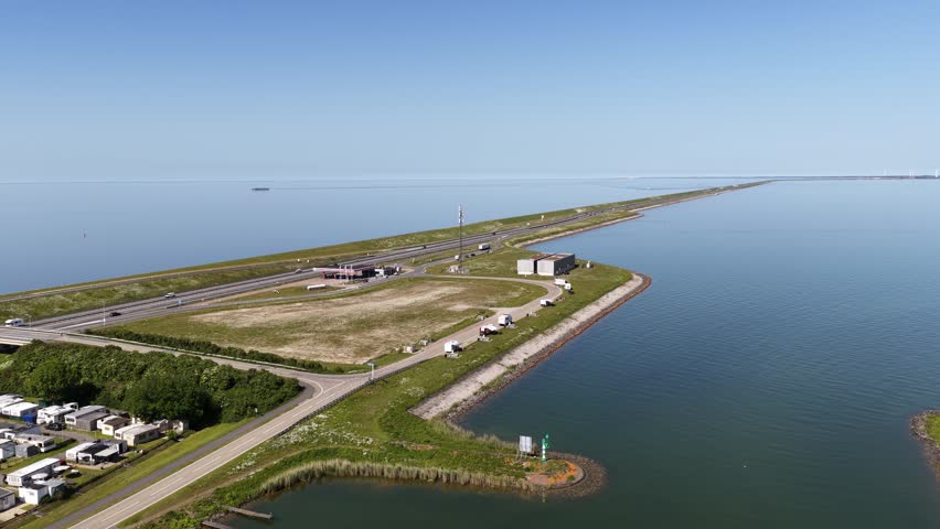 Stunning aerial perspective revealing the afsluitdijk, a major causeway in the netherlands, with cars driving on the highway separating the calm freshwater ijsselmeer from the wadden sea
