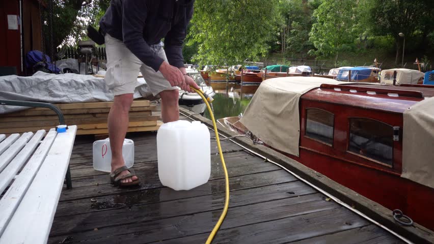 Stockholm, Sweden A man fills water jugs with potable water from a marina for a camping trip on a boat. 