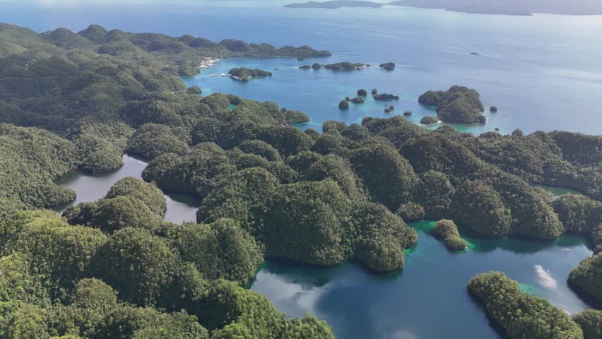 Breathtaking wide-angle aerial drone view of numerous small, dome-shaped jungle islands scattered across a calm, clear turquoise ocean lagoon with visible coral reefs in Siargao, the Philippines.