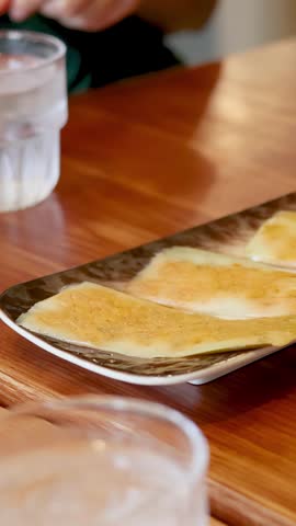 Close-up shot of crispy rice crepes on a plate under warm indoor restaurant lighting.