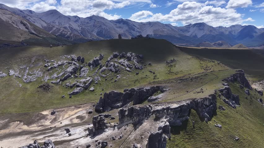 Rocky outcrops and rolling hills stretch across a mountain valley on New Zealand South Island