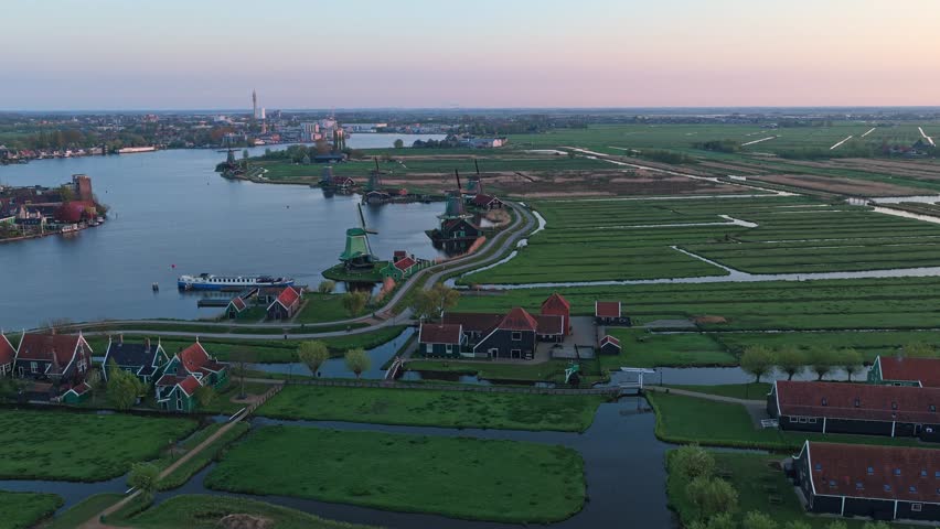 Aerial view moving forward showing the iconic windmills, charming wooden houses, and serene canals of zaanse schans village in the netherlands