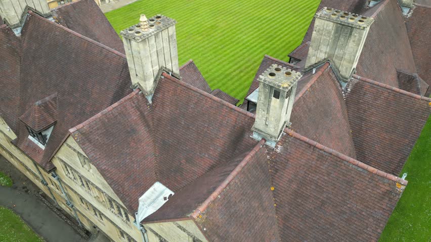 A drone footage of Wills Hall at the University of Bristol, showing historic architecture, green fields and tree-lined paths on a sunny day in England