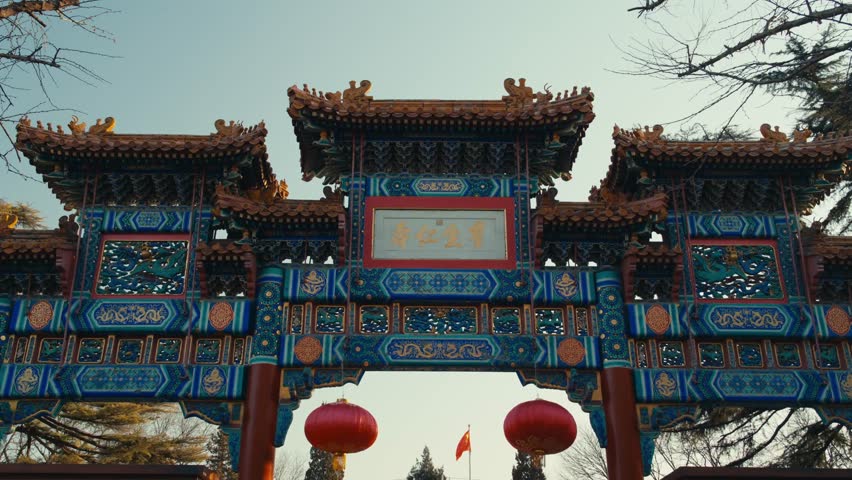 Beijing Yonghe Lama Temple: Elaborate Traditional Chinese Paifang Gateway Featuring Intricate Blue and Gold Woodwork, Imperial Roofs, and Hanging Red Lanterns
