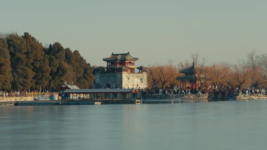 Beijing Traditional Chinese pavilion and ancient watchtower architecture situated along the frozen shoreline of the Summer Palace