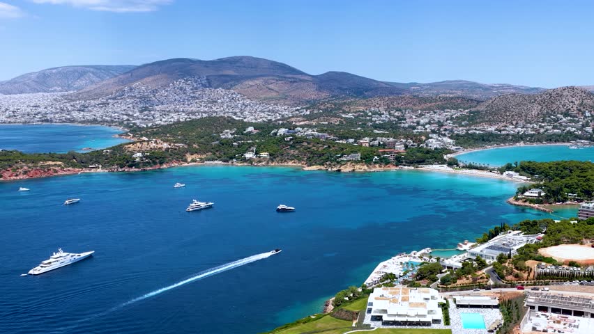 Aerial view of the popular Astir Bay and Beach in Vouliagmeni, south Athens coast, Greece, with turquoise sea and moored luxury yachts during summer time