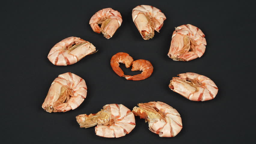 Peeled dried shrimps forming a heart shape, surrounded by unpeeled prawns rotating.