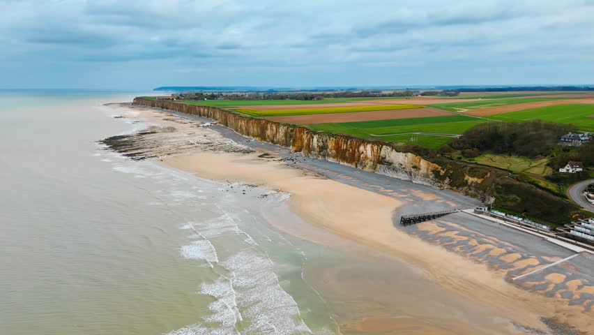 Rural fields meeting cliff edge above English Channel coast in Normandy, France. Drone view of coastal landscape and beach