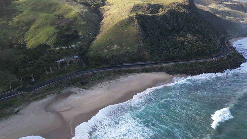 Scenic aerial view of Great Ocean Road Australia with winding highway through mountains and hills above the Southern Ocean coastline