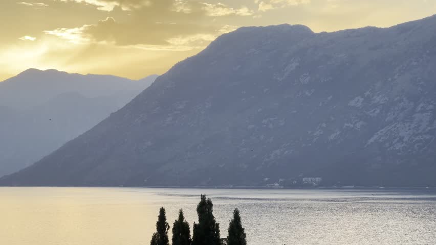 Beautiful golden sunset over magnificent mountains and a calm lake or sea bay, golden hour, Kotor Bay, Montenegro