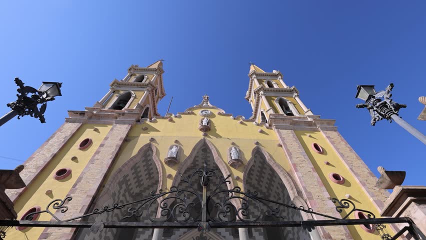 Beautiful low angle view of the ornate yellow facade and twin steeples of the Cathedral Basilica of the Immaculate Conception in the historic center of Mazatlan Mexico