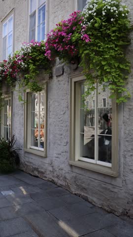 Charming view of a historic stone house facade adorned with vibrant hanging flower boxes on a street in Old Quebec City Canada