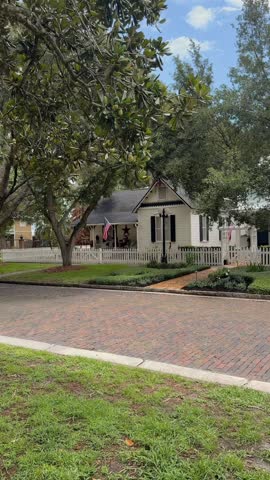 Classic American white cottage with a picket fence and brick street view