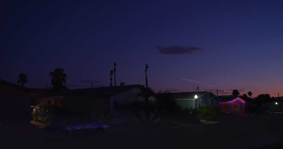 Rocket launch ascends the twilight sky over and beyond a colorful nondescript neighborhood community at twilight. June 24 launch. 