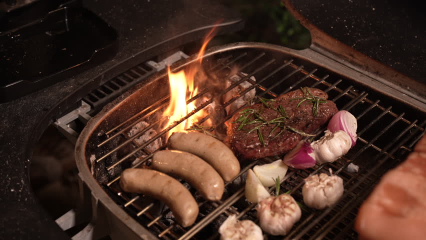 Barbecue grill sausage flame garlic onion meat smoke fire grate outdoor rustic cooking with steak rosemary savory food preparation over bright hot metal grate