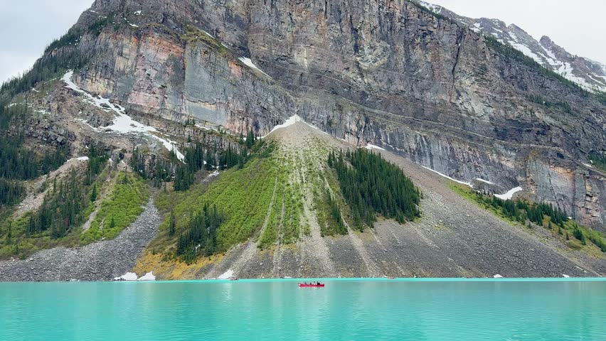 Views of Moraine Lake surrounded by tall mountains and lush trees. The lake