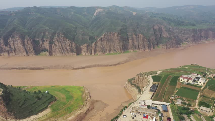 Aerial video footage of the scenic Yellow River flowing through dramatic canyons and sandstone cliffs in Inner Mongolia, China.