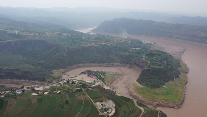 Aerial video footage of the scenic Yellow River flowing through dramatic canyons and sandstone cliffs in Inner Mongolia, China.
