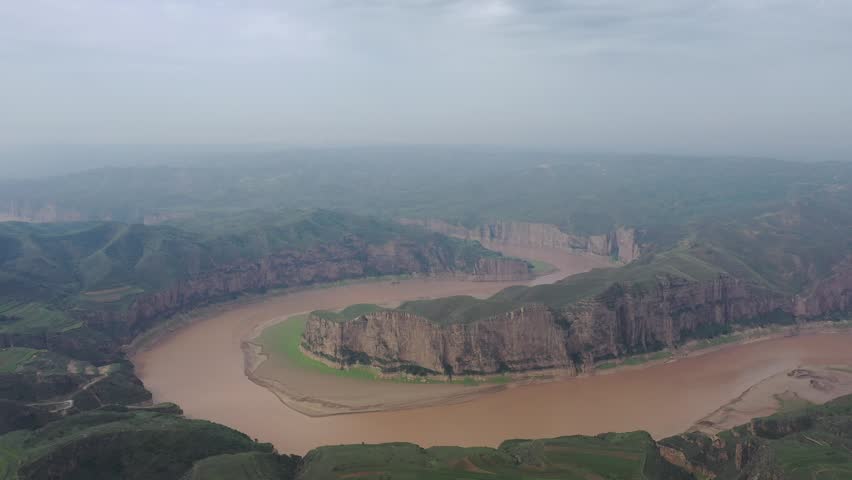 Aerial video footage of the scenic Yellow River flowing through dramatic canyons and sandstone cliffs in Inner Mongolia, China.