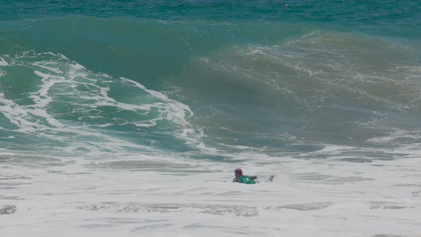 Surfer ducking under big wave