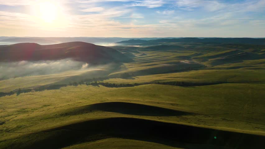 Landscape with green mountains, mist at dawn, and clouds