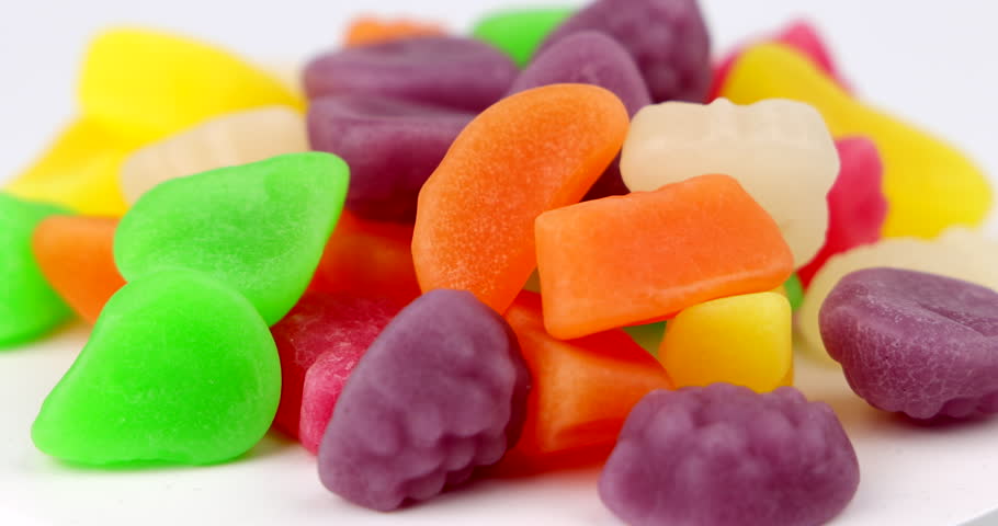 Horizontal camera perspective of various fruit shaped gummy candies spinning on a rotating plate surface during a birthday party