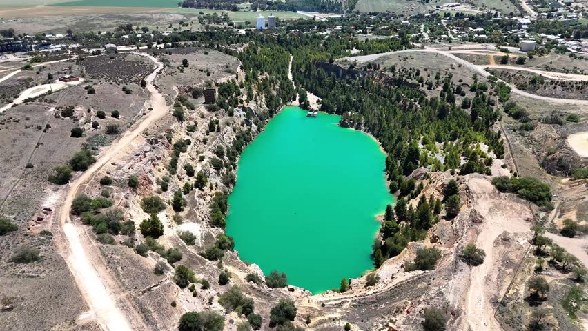 An aerial footage of the old Burra copper mine with green lagoon surrounded by rural land on a sunny day in mid-northern South Australia