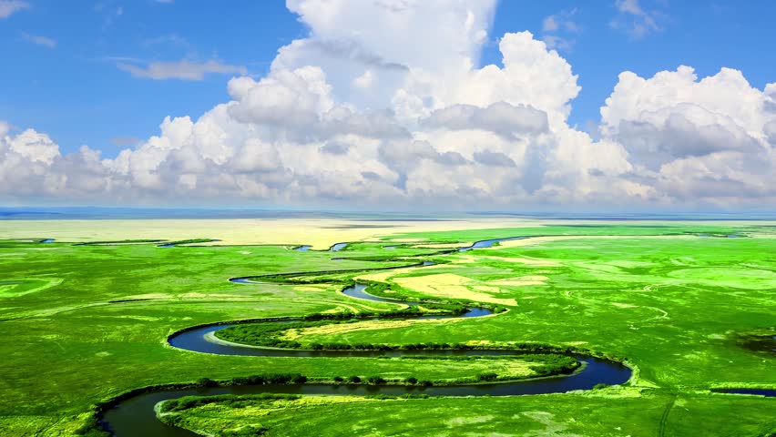 Time lapse of zigzag river wetland grassland in China Inner Mongolia,long white clouds spread all over sky and drift slowly,yellow green meadow stretches boundlessly without birds