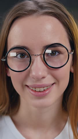 Closeup pretty girl looking at camera smiling and takes off glasses in modern kitchen at home. Slow motion.