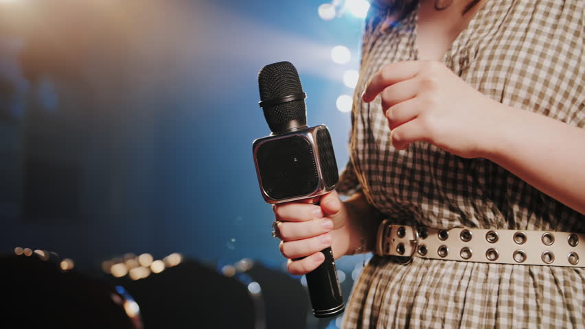 Woman Tapping Microphone with Finger to Test Sound on Theater Stage