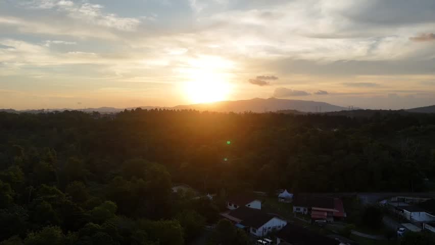 Aerial drone footage of a beautiful sunset over a suburban residential neighborhood with distant hills and dramatic clouds in Johor Bahru, Malaysia. Golden hour landscape captured from above in vertical format