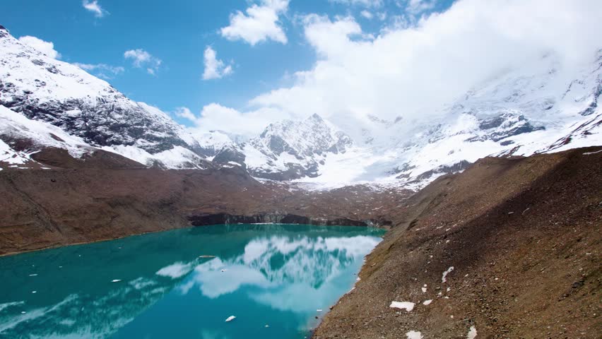 4K Aerial view of Ghepan lake surrounded by snowy mountains in Lahaul, Himachal Pradesh, India. Majestic blue mountain lake with reflection of mountains in water. Beautiful nature landscape. 