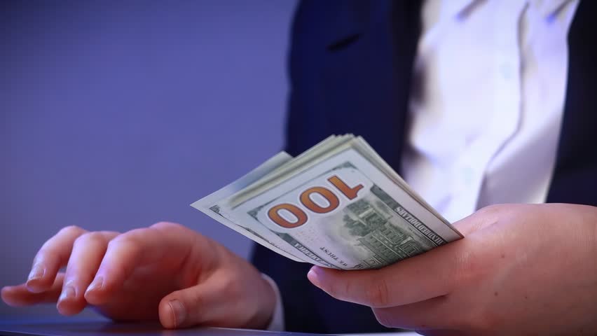 Hands hold money while a bright idea appears in the air above, showing a moment of inspiration at a business event during the day.