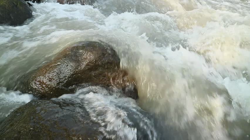 strong water flow in a rocky river in the afternoon