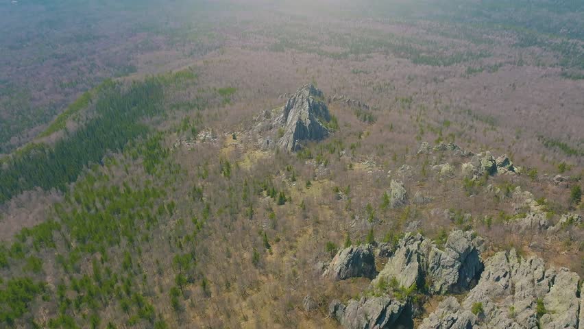 Drone footage of a rocky mountain ridge surrounded by taiga forest in Taganay National Park near Zlatoust, Chelyabinsk Oblast, Russia, spring landscape