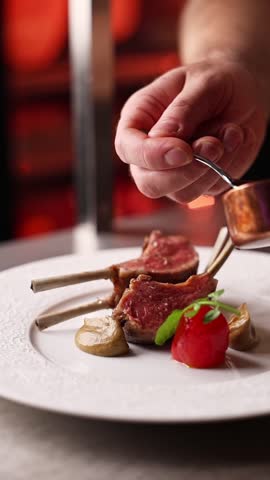 Chef preparing grilled New Zealand lamb ribs in a premium restaurant kitchen. Close-up of juicy meat, fire grill and gourmet cooking process.