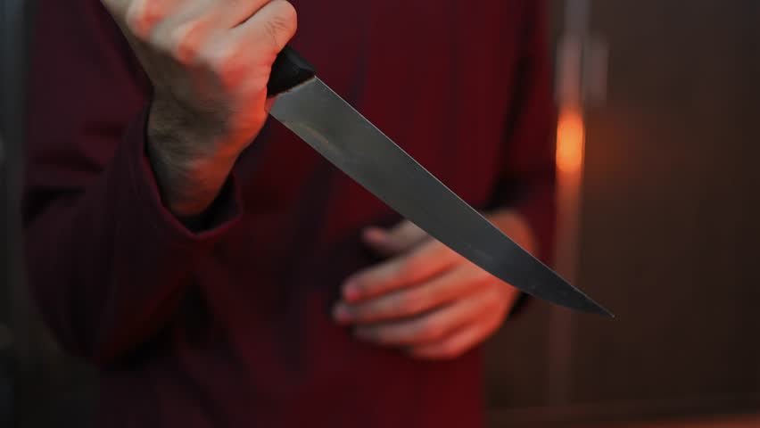 Close Up of Hand Holding Kitchen Knife with Blurred Background