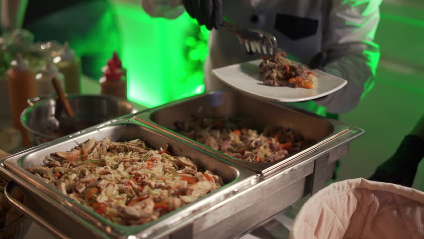 A waiter serves a plate of food at an elegant buffet at a wedding reception.